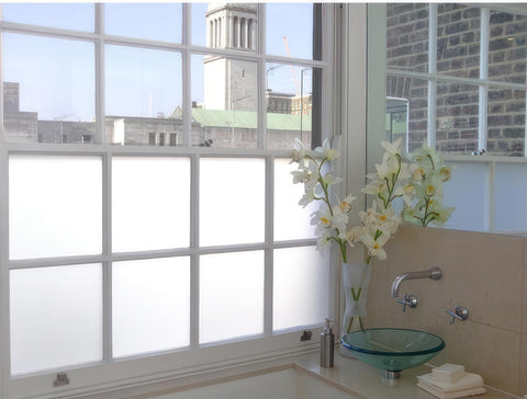 White frosted window film applied to the lower panes of a sash window, providing daytime privacy while still allowing natural light into a stylish modern bathroom.
